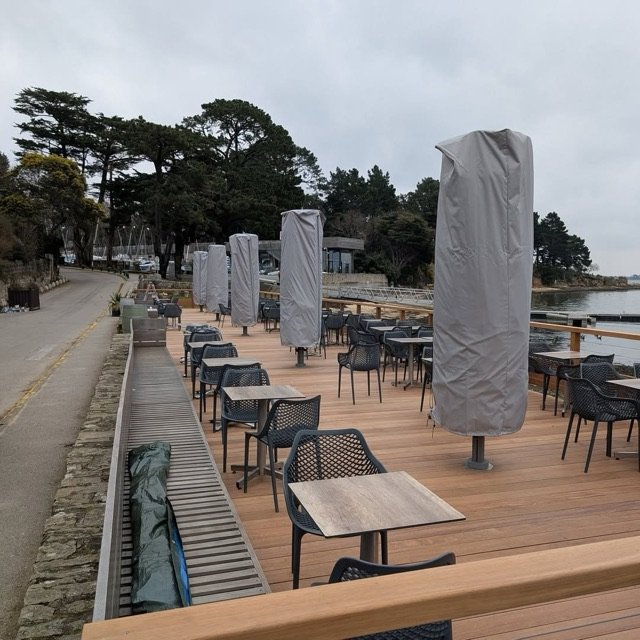 Parasols Prostor repliés sous housse sur la terrasse en bois du restaurant