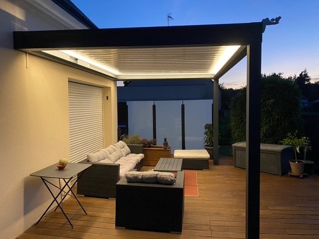 Pergola bioclimatique avec LED au-dessus d'un salon de jardin à Bohal