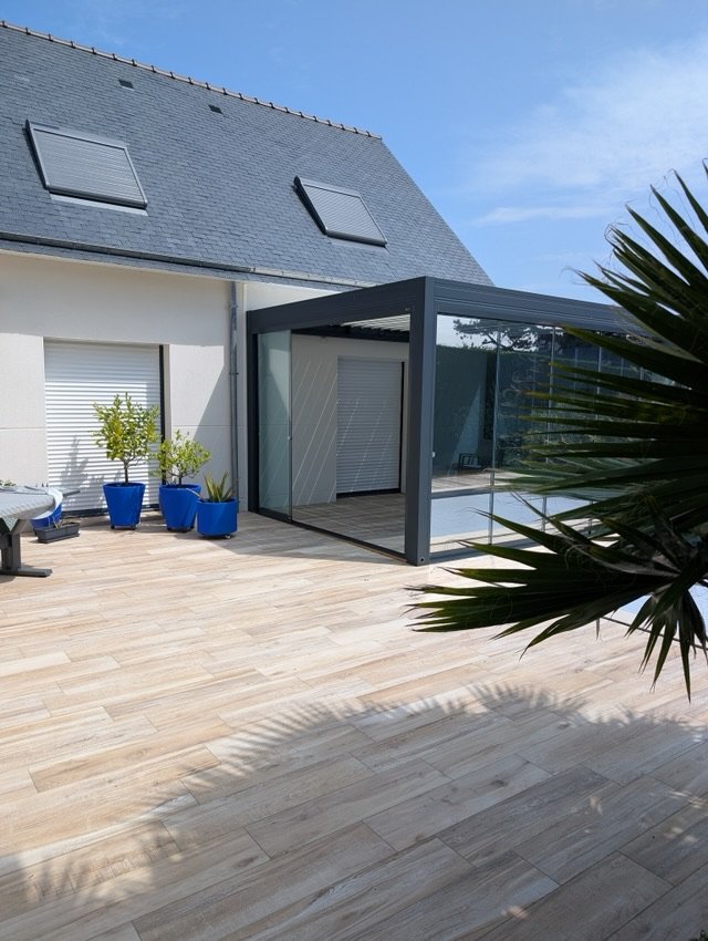 Pergola anthracite fermée de vitrages coulissants sur une terrasse à Quiberon