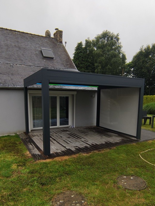 Pergola bioclimatique anthracite avec store zip baissé sur le côté, pays de Lorient