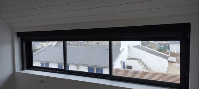 Store enrouleur intérieur remonté au-dessus d'une baie vitrée avec vue sur Quiberon